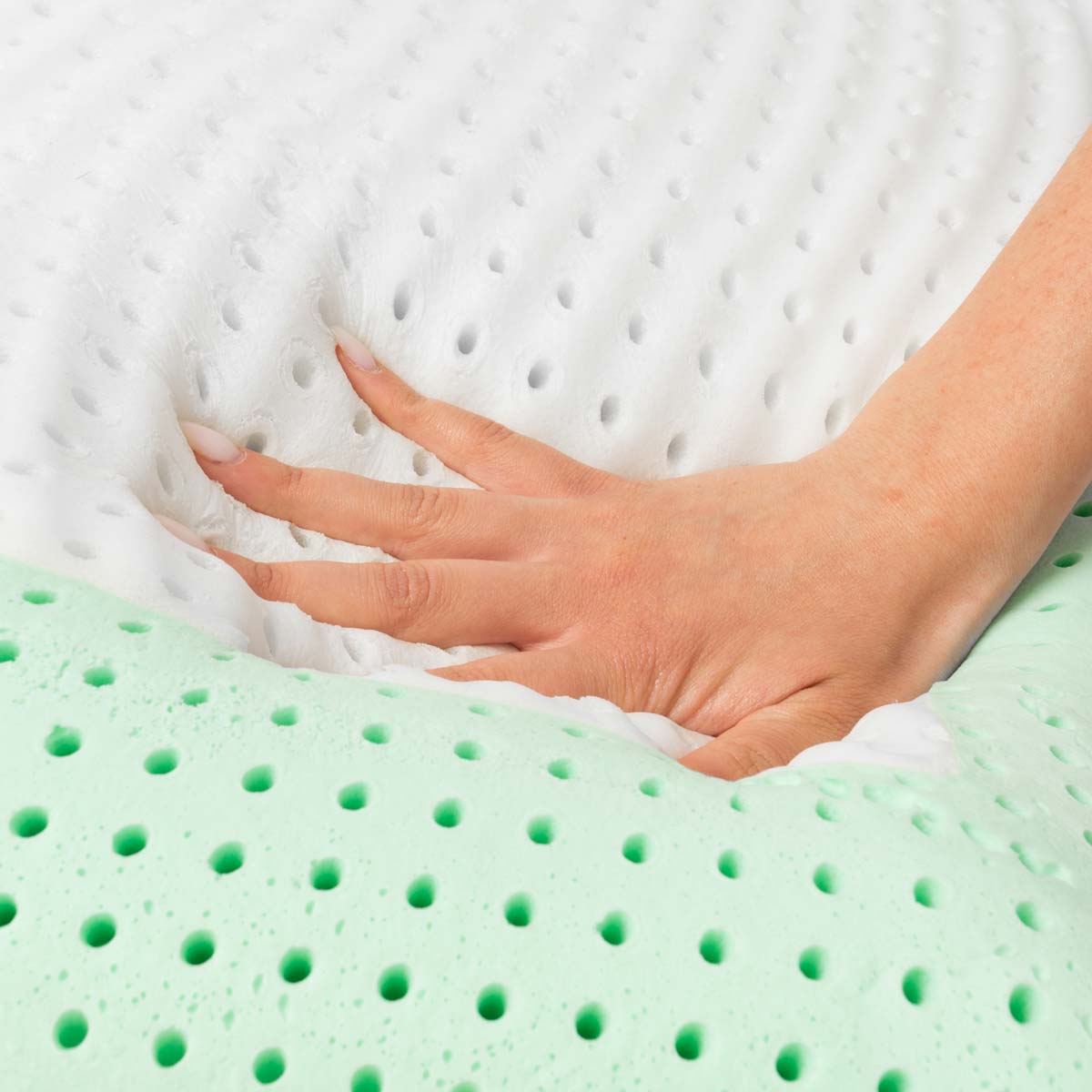 Una mano preme su un materasso verde e bianco perforato.