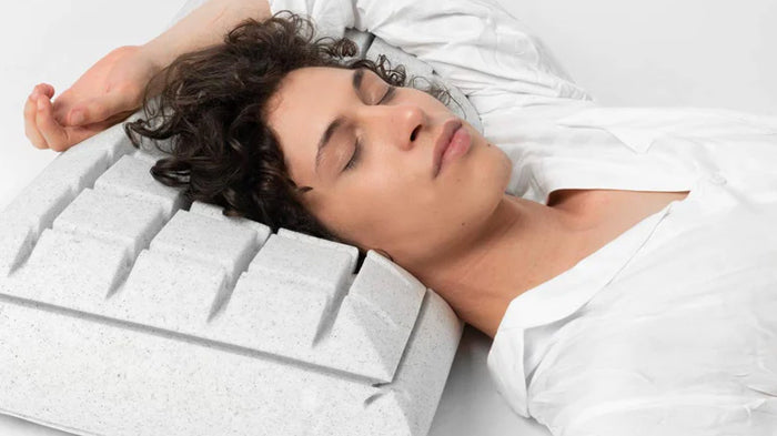 Una persona dorme su un cuscino ergonomico grigio.