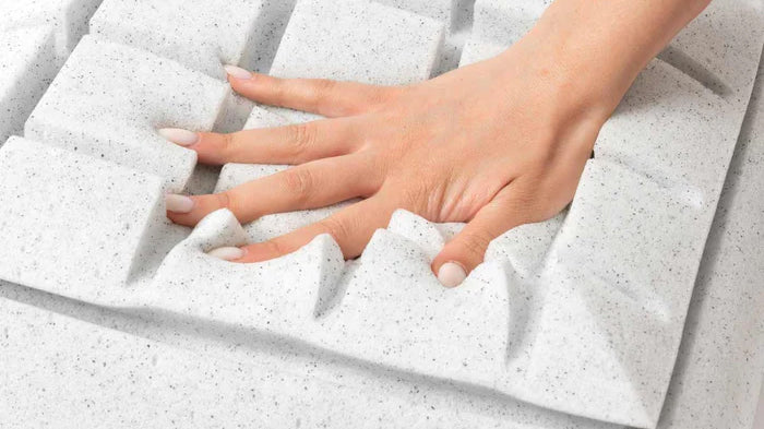 Una mano preme una superficie di schiuma bianca.